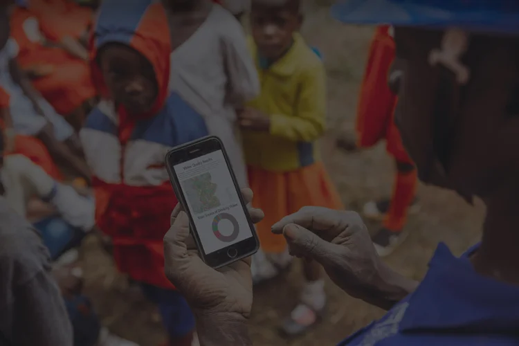 A field worker records a water point on a mobile phone during a site visit in Uganda